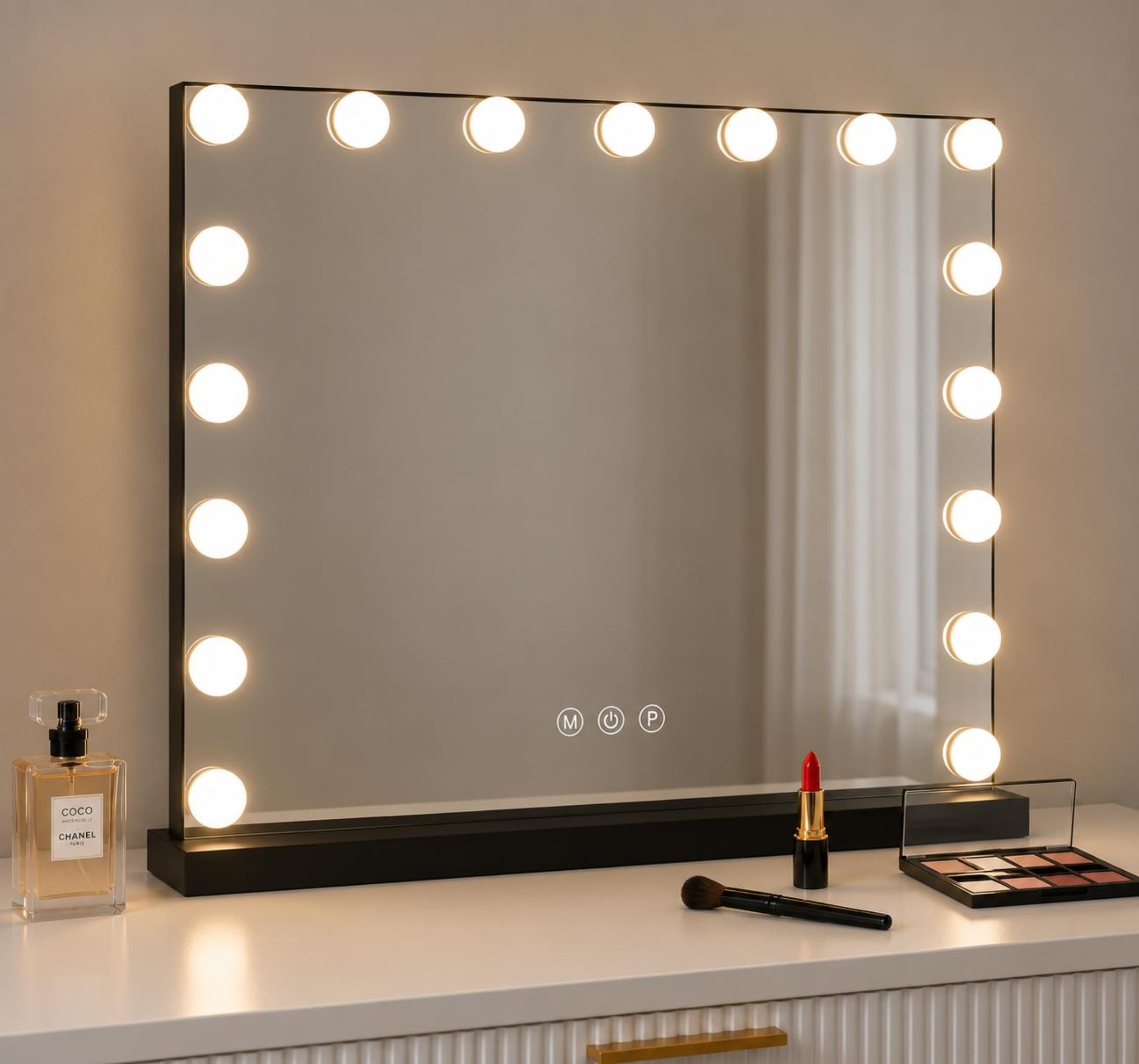A rectangular vanity mirror with a black frame and glowing round light bulbs around the border, placed on a white dresser with cosmetics nearby.